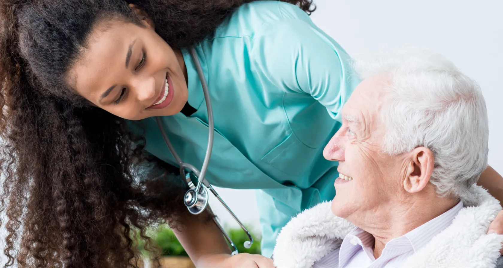 A caregiver smiling warmly with an elderly client